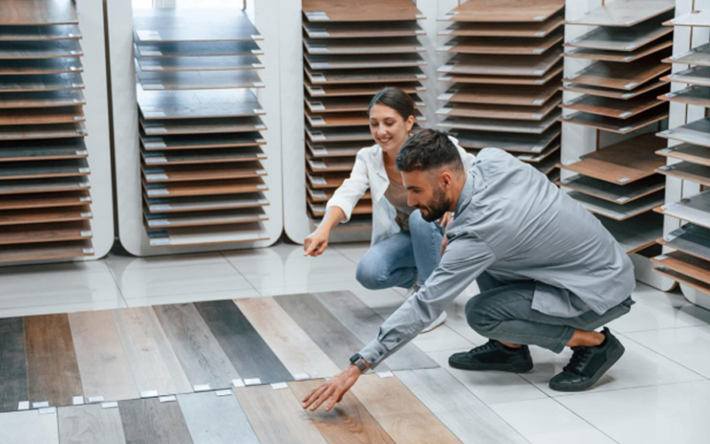  Customers comparing the textures and colors of vinyl plank flooring.