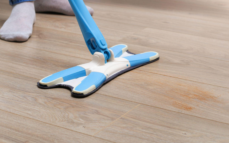 A man washes the floors with a mop in a room.