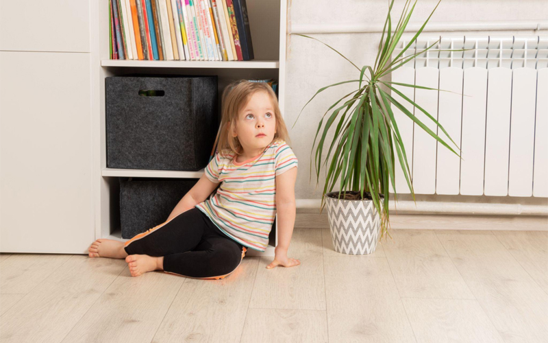 Child sits on the floor in the room near the bookcase